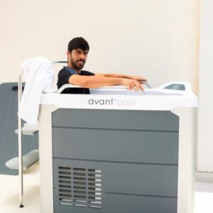 A man relaxes in an Avantopool Kinos hydrotherapy tub, a towel draped on the side and a ladder in the background.
