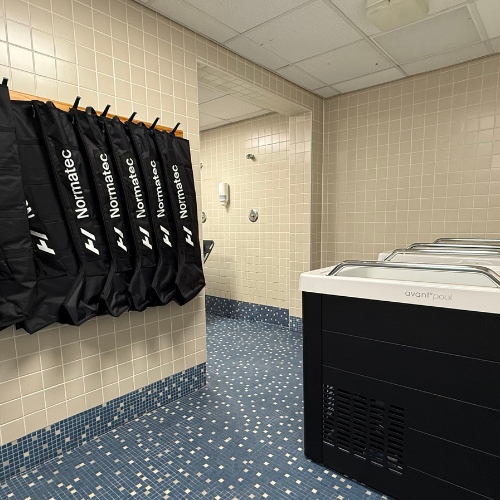 A tiled room with four Normatec recovery boots hanging on the wall and an Avantopool cold plunge tub on the right—perfect for athletes preparing for or recovering after the intensity of the All-Ireland Final Weekend, embodying the dedication seen across Irish sport.