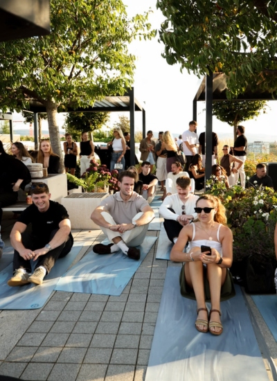 A group of people sitting on mats outdoors under trees during a breathwork session at the Eden One launch.