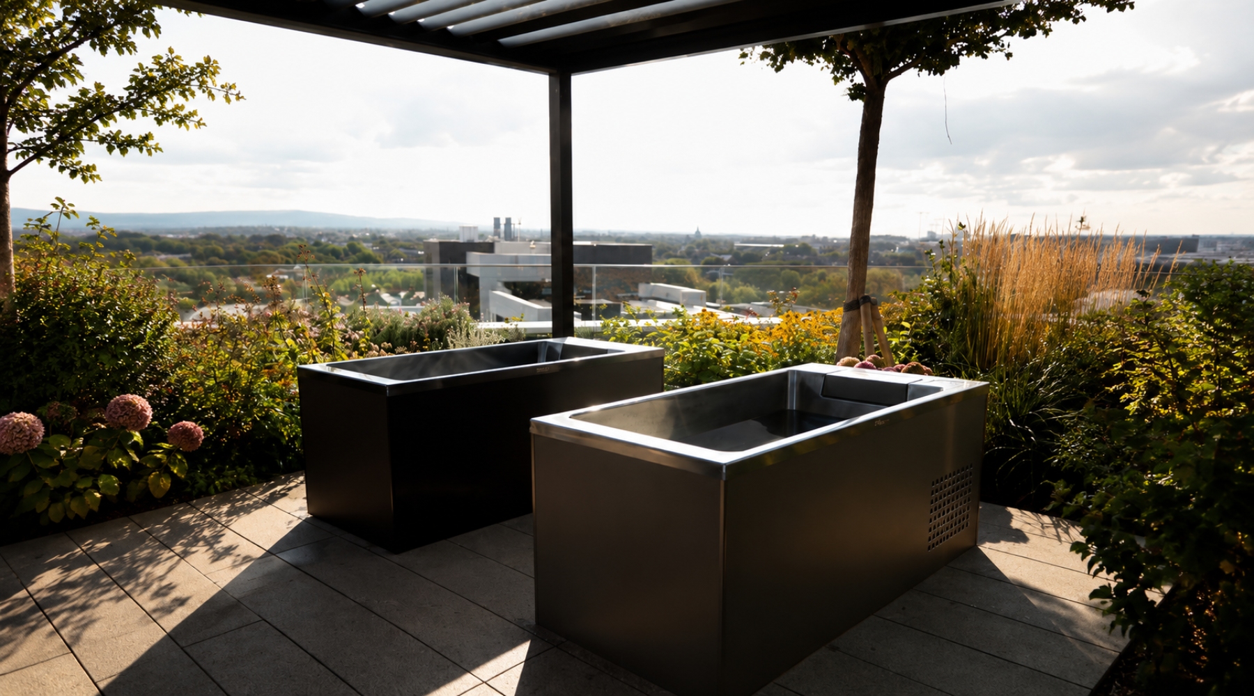 Two Kuura cold plunges on a tiled rooftop patio under a pergola, with the Dublin skyline in the background.